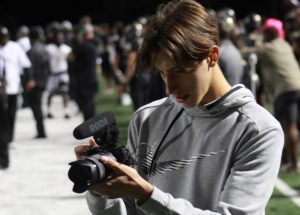 Michael Suchici (12) on the sideline videos the game to put on his instagram channel. 